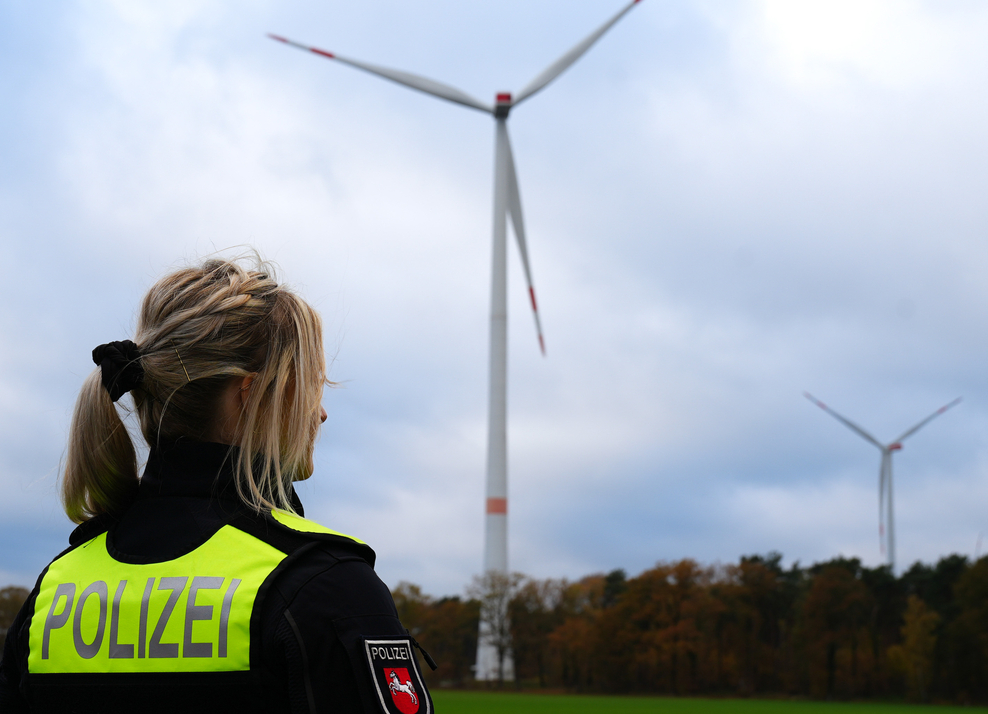 Polizistin steht vor Windkraftanlage